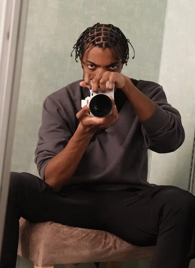 Destin Tucker seated, aiming a camera into a mirror