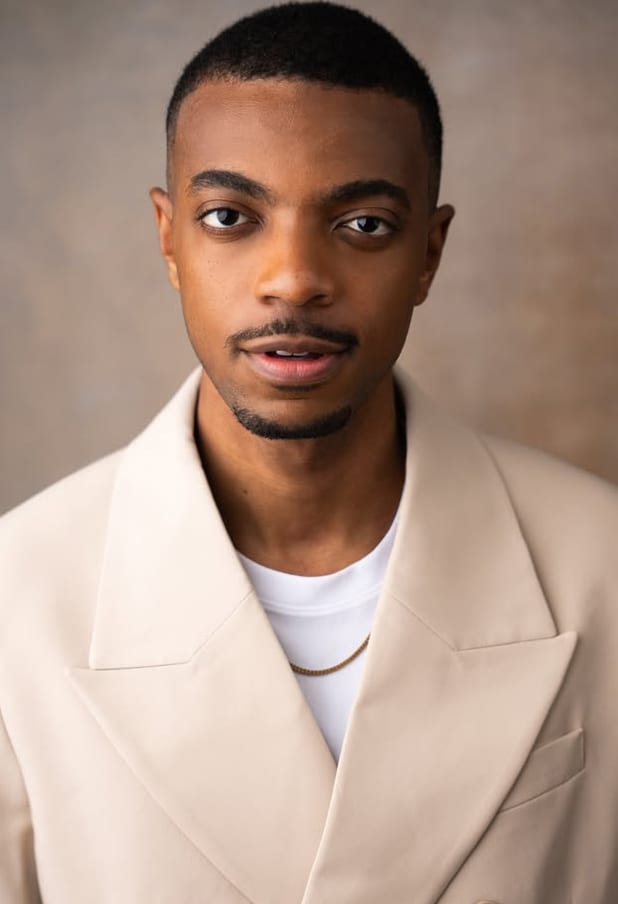 Destin Tucker in a cream suit, looking into the camera